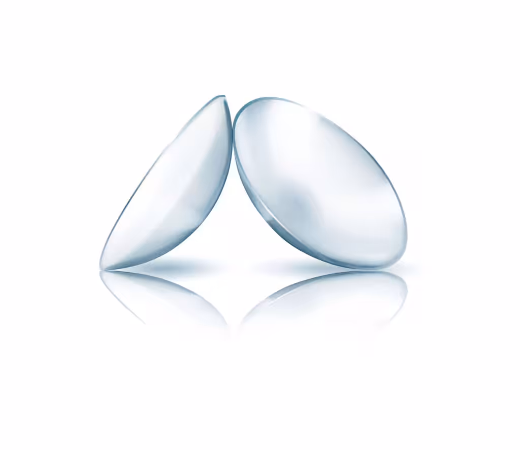 Dvě průhledné měkké kontaktní čočky s odrazem na bílém pozadí.